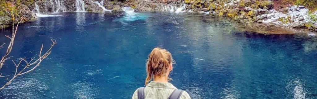 Image shows a young woman gazing into the ethereal beauty of The McKenzie River's Tamolitch Blue Pool in Oregon - photo by Chris  LaVoie
